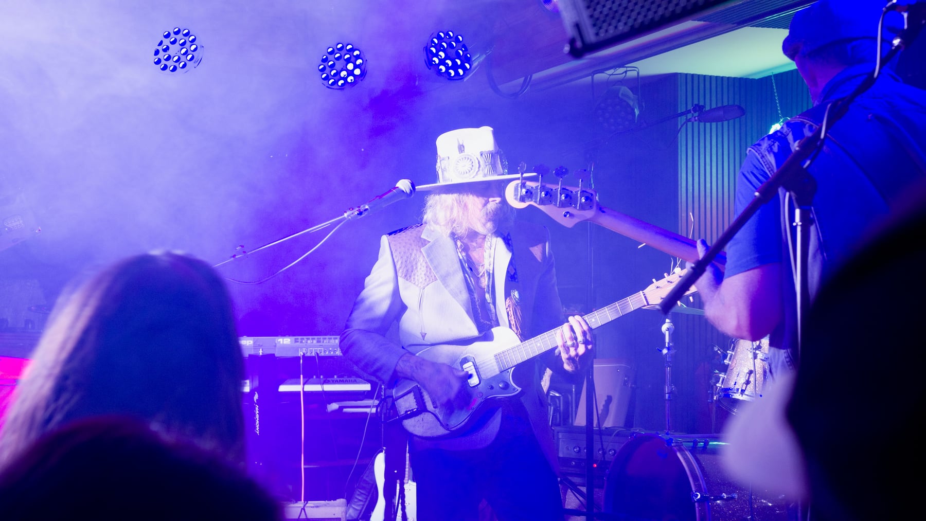 Guitarist in a white hat performing under blue lights at Ivan'z House